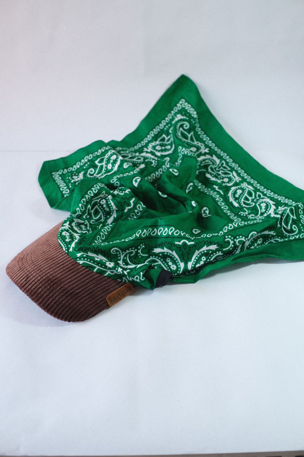 Green paisley bandana fabric spread open over corduroy brim on Eclipse Forest Print Kapri