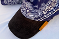 Close-up of navy paisley bandana fabric meeting black corduroy brim on Knotycap cap